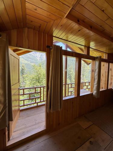 an empty room with windows in a log cabin at Avasaa Café and Stay in Jibhi
