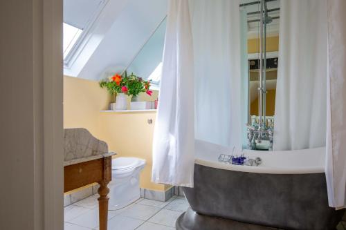 a bathroom with a tub and a toilet and a sink at Saratoga Cottage in Bruern
