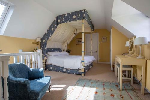 a bedroom with a canopy bed and a chair at Saratoga Cottage in Bruern