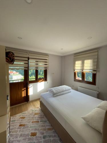 a bedroom with a large bed and two windows at AYDER Köroğlu Apart in Ayder Yaylasi