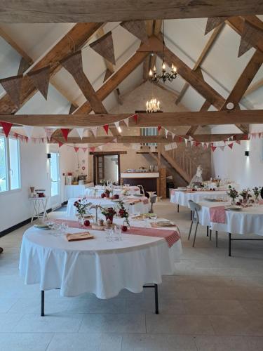 a large room with tables with white tablecloths at Espace st andre in Douadic