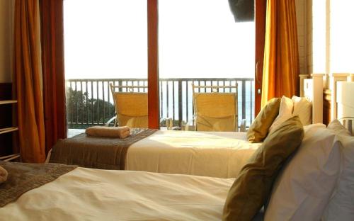 two beds in a hotel room with a balcony at Sea La Vie Ponta do Ouro in Ponta do Ouro