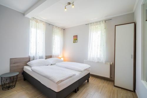 a bedroom with a bed with white sheets and a mirror at Riviéra Apartmanház in Siófok