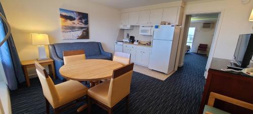 a living room with a table and a kitchen with a refrigerator at Mariner Inn And Suites in Kill Devil Hills