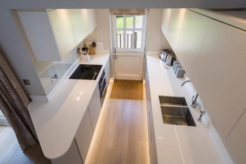 eine Küche mit weißen Schränken und Holzböden in der Unterkunft 5 Keeper's Cottage, Hillfield in Dartmouth