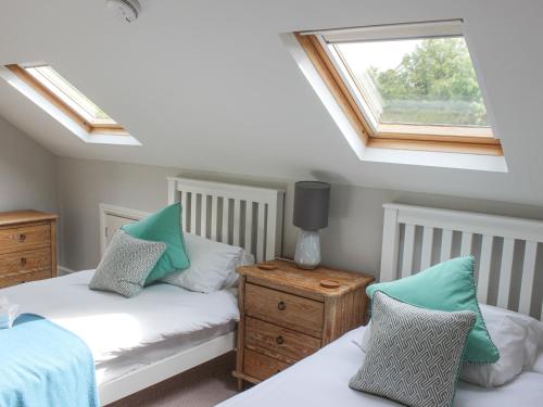 ein Schlafzimmer im Dachgeschoss mit zwei Betten und einem Fenster in der Unterkunft 5 Keeper's Cottage, Hillfield in Dartmouth