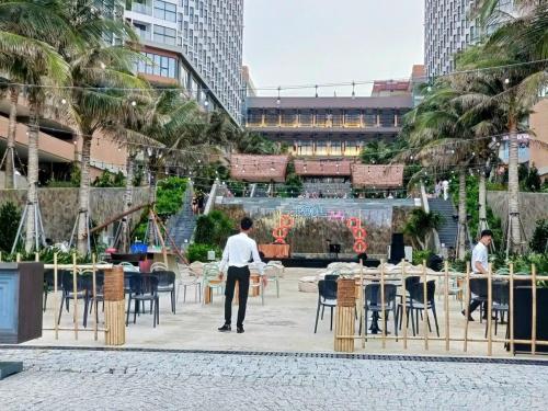 a man standing in a courtyard with tables and chairs at APEC MANDALA Condotel in Phan Thiet