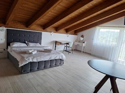 a bedroom with a large bed and a table at Pensiunea Casa de pe Vale in Vulcan