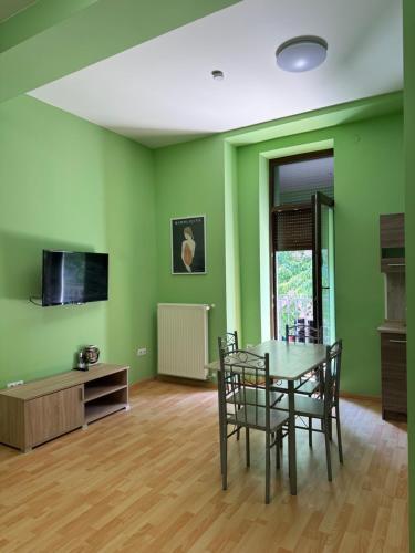 a dining room with green walls and a table and chairs at Heviz Gracia Apartment in Hévíz