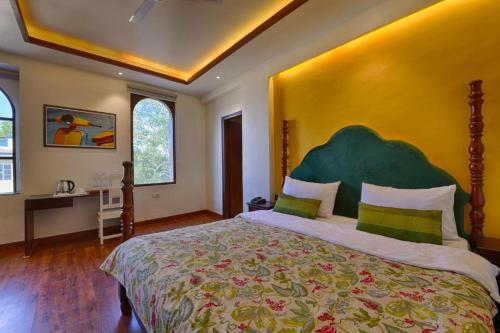 a bedroom with a large bed with a green headboard at Gulmohar Mansion - A Boutique Stay in Jaipur