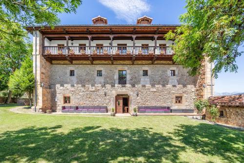 an exterior view of a large stone building with a balcony at La Torre de Perrozo in Cabezón de Liébana