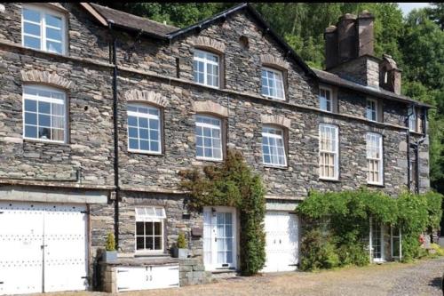 an old stone house with a white garage at Croft Courtyard, Ambleside in Ambleside