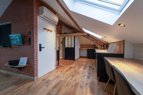a loft conversion with a brick wall and a window at Evasion chic, spa et sauna sous les toits in Nancy