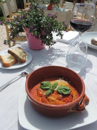 a bowl of soup on a table with a glass of wine at Torre Fiore Hotel Masseria in Pisticci