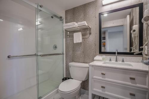 a bathroom with a toilet and a sink and a shower at Monte Carlo Inn Oakville Suites in Oakville