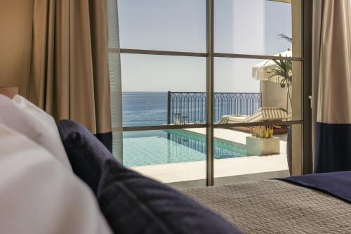 a man laying on a bed looking out a window at the ocean at Sewelo Suites - Beachfront Boutique Suites in Skinária