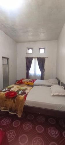 a bedroom with two beds and two windows at Vernando Homestay in Bajawa