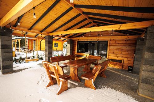 a wooden table and chairs in the snow on a cabin at Świerkówka in Siemianówka