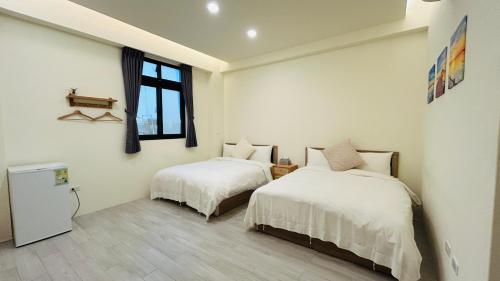a bedroom with two beds and a window at Full of Fun in Magong