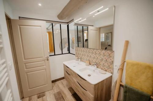 une salle de bain avec un lavabo et un miroir dans l'établissement Gîte du Bief, à Pluvigner