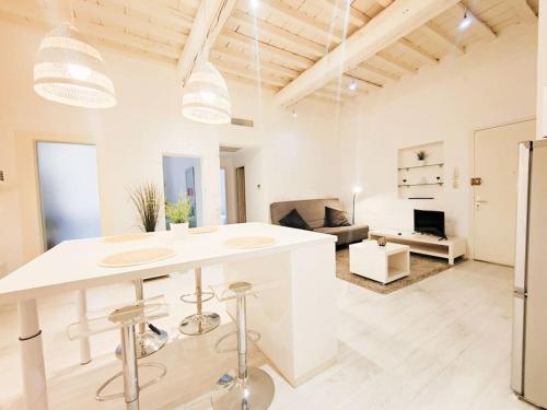 Il comprend une cuisine et un salon avec des murs blancs et une table. dans l'établissement Appartement Le Flocon 2 chambres Maison Carrée Centre historique, à Nîmes