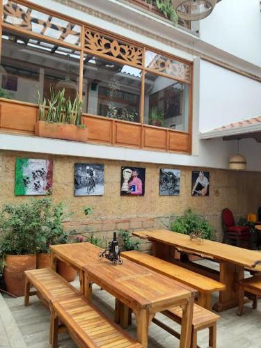 a restaurant with wooden benches and pictures on the wall at Hotel El Giro in Villa de Leyva
