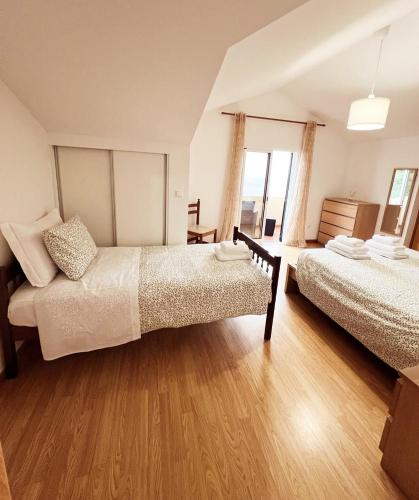 Un dormitorio con dos camas y suelo de madera. en Villa Abreu, en Ponta do Sol