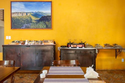 a dining room with a table and chairs and a painting at Pouso da Trilha Hospedagem in Lençóis