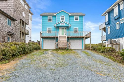 a blue house on a street with two buildings at Renegade - Oceanfront and Allows Pets! in Surf City
