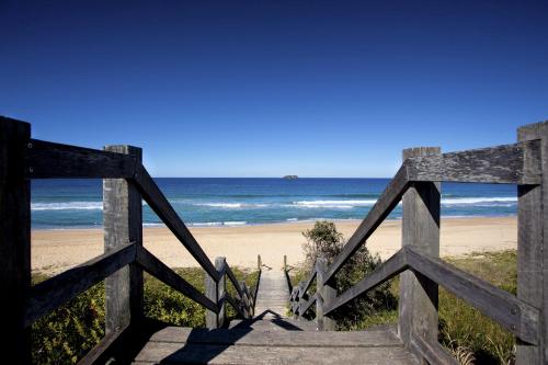 a wooden gate leading to a beach with the ocean at Sapphire Beach Holiday Park in Coffs Harbour