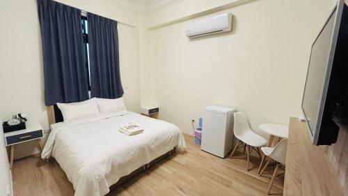 a bedroom with a white bed and a television at Full of Fun in Magong