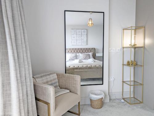 a mirror in a bedroom with a chair and a bed at West Lodge, Bognor Regis in Bognor Regis