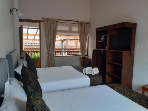 a hotel room with two beds and a television at Hotel El Giro in Villa de Leyva