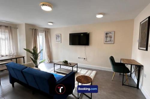 a living room with a blue couch and a tv at Modern 2 Bedroom Flat By Tara Stays Short Lets & Serviced Accommodation Watford With Free Parking & Nearby Warner Studios in Watford