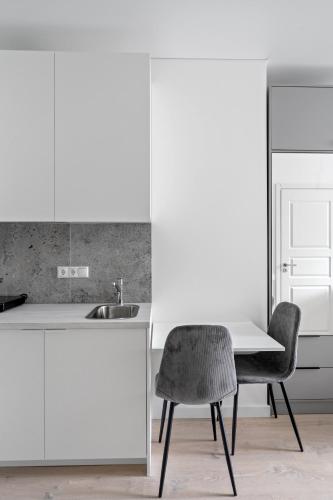 a kitchen with a sink and a table and a chair at Central Cozy 1Bedroom Apartment with Sofa Bed - Sleeps 4 in Vilnius