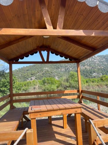 a wooden picnic table on a deck with a roof at 101 Gün Kiralık Havuzlu Lake House kayacık in Dalaman