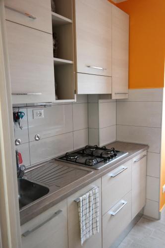 a kitchen with white cabinets and a stove and a sink at Appartamento al Condominio Concordia in Grado