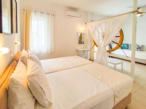 a white bedroom with two beds and a window at Al Mar in Skiathos Town