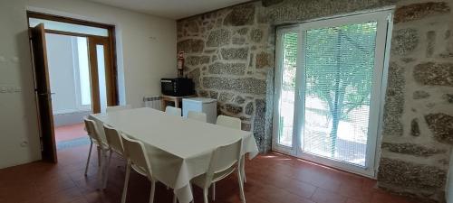 a dining room with a white table and chairs at Casa Roupar by Gerês Casas in Terras de Bouro
