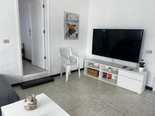 a living room with a flat screen tv and a chair at El graciosero in Caleta de Sebo