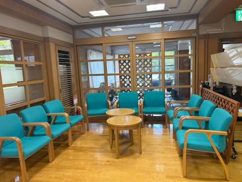 a waiting room with blue chairs and tables and windows at Asakusa Sanso in Uonuma