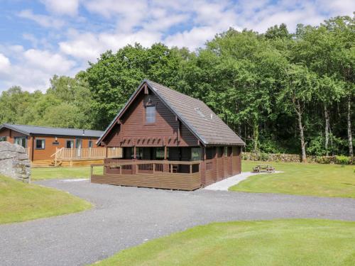 a large wooden building in a yard with trees at Moyle Lodge in Dalbeattie