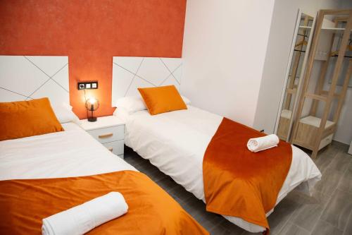 1 Schlafzimmer mit 2 Betten mit orangefarbener und weißer Bettwäsche in der Unterkunft Pregonero Urban Suites - Naranja in Soria