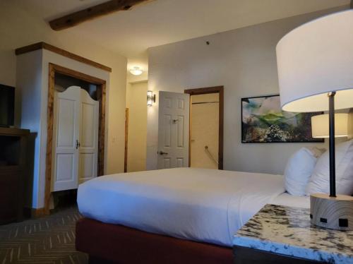 a bedroom with a large white bed and a lamp at The Lodge at Breckenridge in Breckenridge