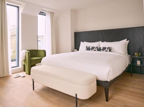 a bedroom with a large white bed and a green chair at The Store in Oxford