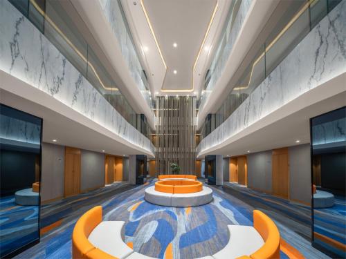 an office lobby with orange chairs and a table at Holiday Inn Express Zhengzhou Zhengdong by IHG in Zhengzhou