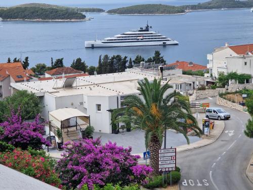 a cruise ship in the water with a town and a palm tree at Apartmens Špiko 2 in Hvar