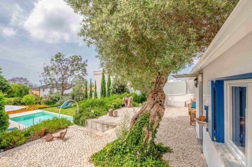 a tree in the courtyard of a house with a pool at GuestReady - Casa do Jacarandá in Paço de Arcos