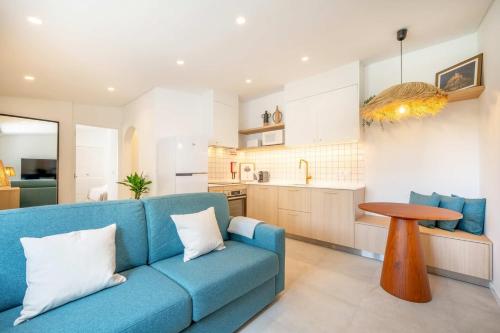 a living room with a blue couch and a kitchen at GuestReady - Casa do Jacarandá in Paço de Arcos