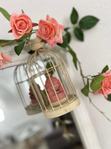 a bird cage with pink roses in it at Korona Apartman Székesfehérvár in Székesfehérvár